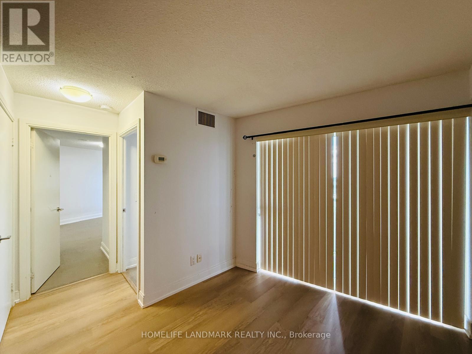 A room with wooden floors and a sliding door with blinds.