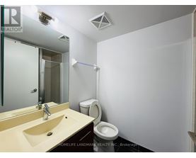 A bathroom with a sink, mirror, toilet and a white wall.