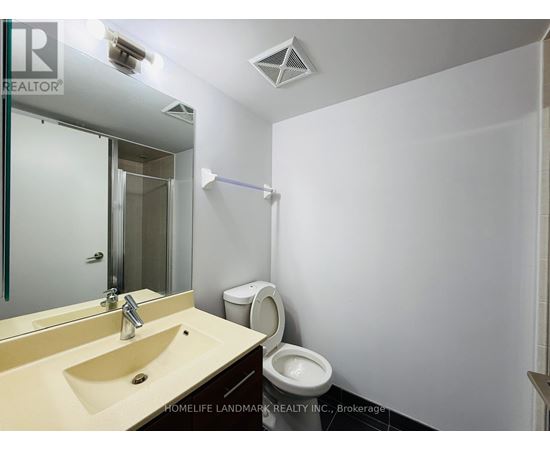 A bathroom with a sink, mirror, toilet and a white wall.
