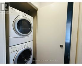 A stack of white front loading washing machines in a small room.
