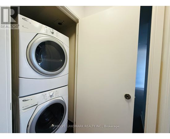 A stack of white front loading washing machines in a small room.