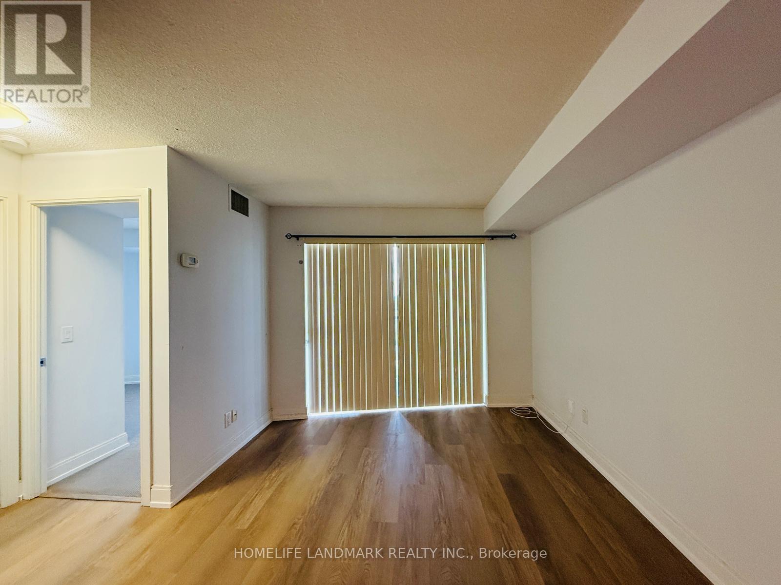 A room with wooden floors and a window with blinds.