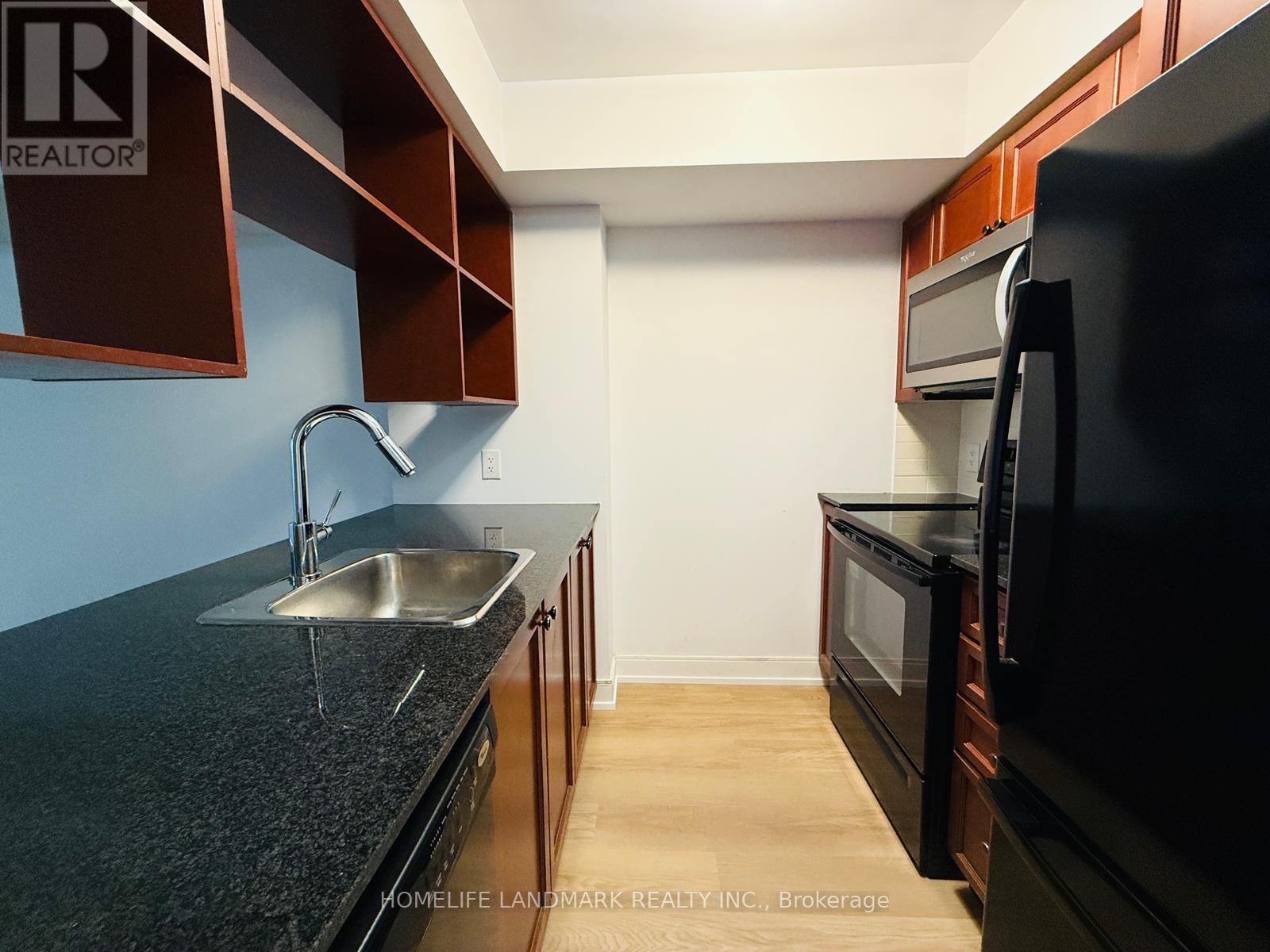 A kitchen with dark brown cabinets and a black countertop.