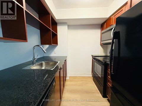 A kitchen with dark brown cabinets and a black countertop.