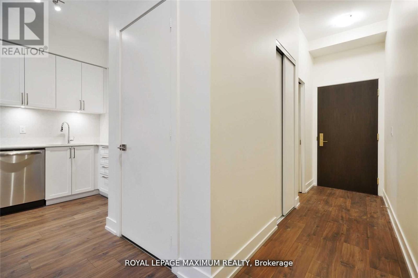 A white kitchen with wooden floors and a white door.