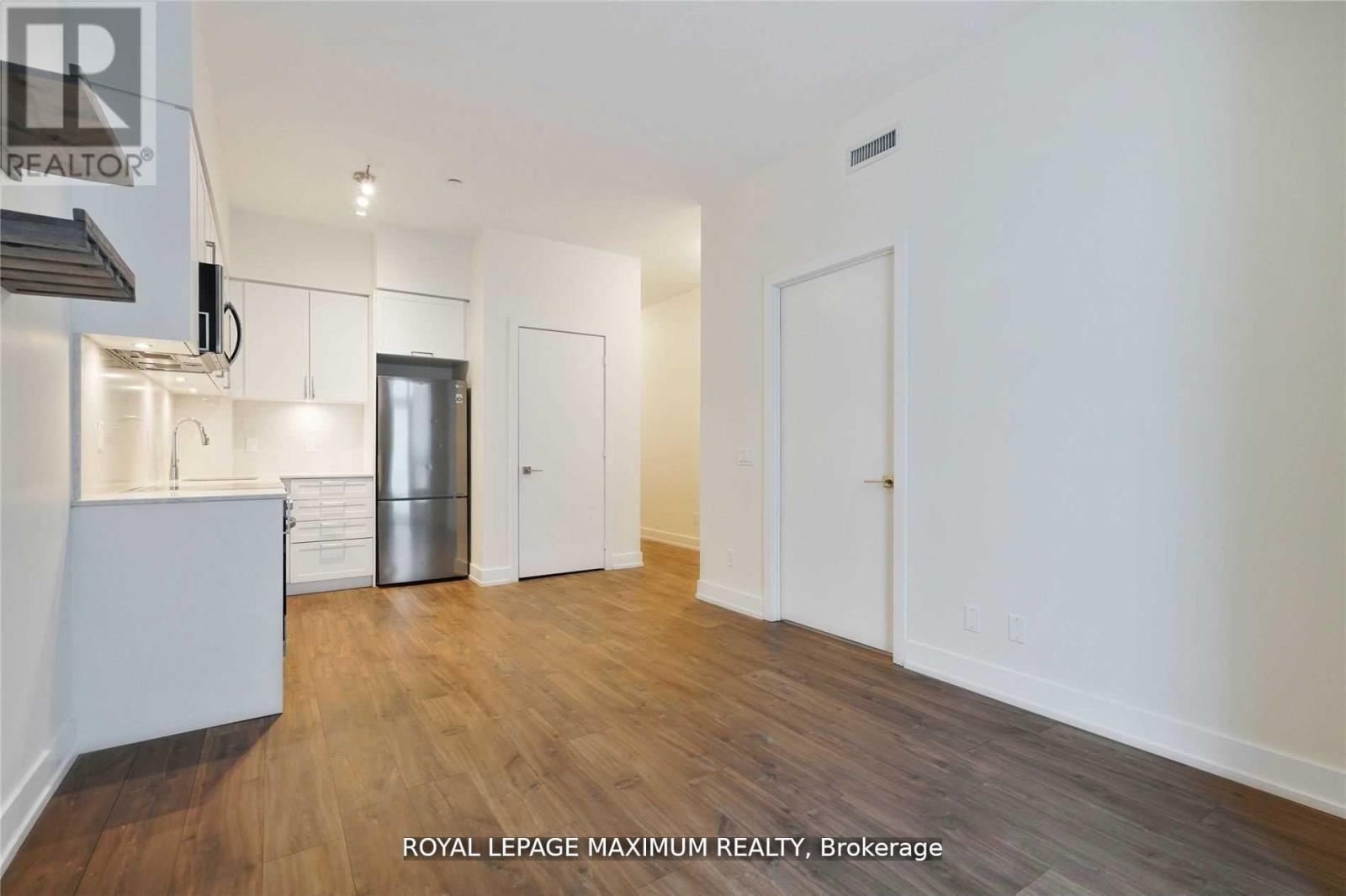 A spacious room with wooden flooring and white walls.