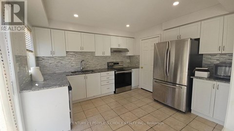 A kitchen with white cabinets and a stone backsplash.