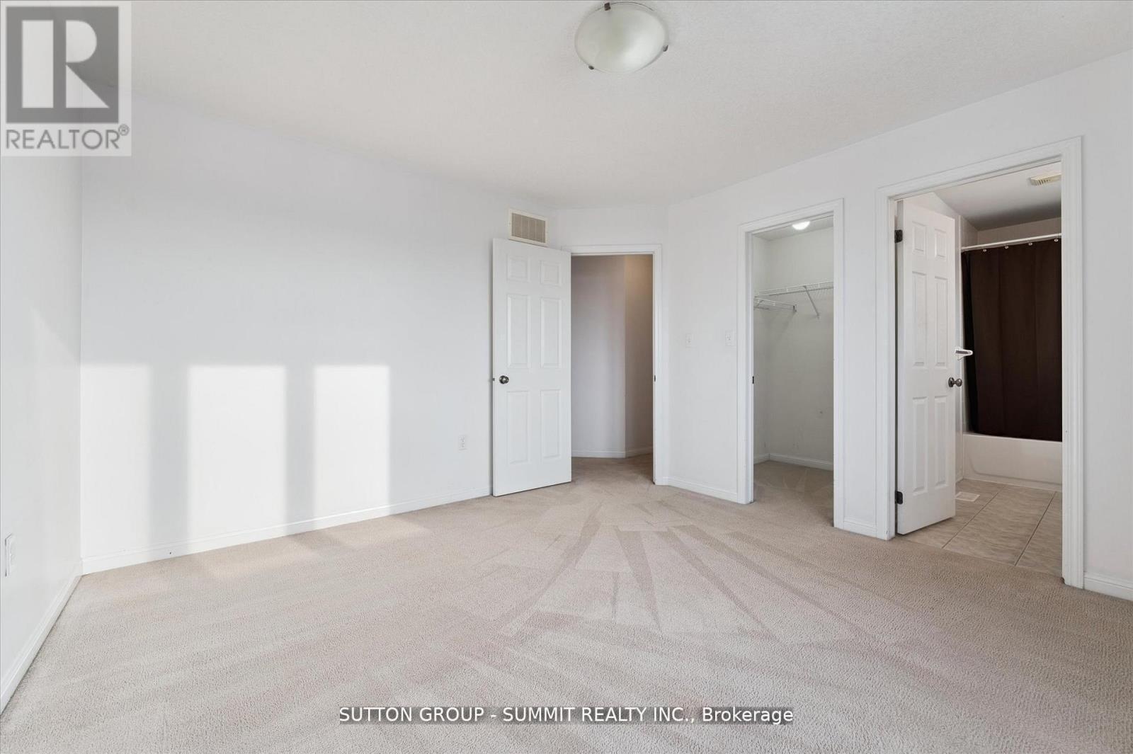 A spacious room with white walls and a carpeted floor.