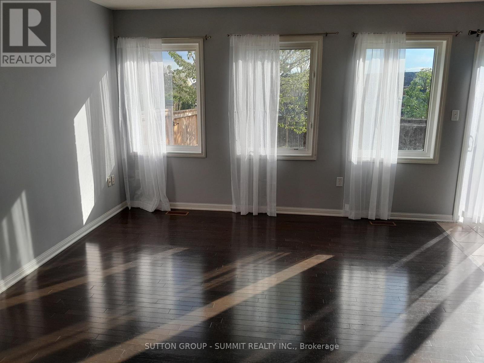 A room with white curtains and wooden flooring.