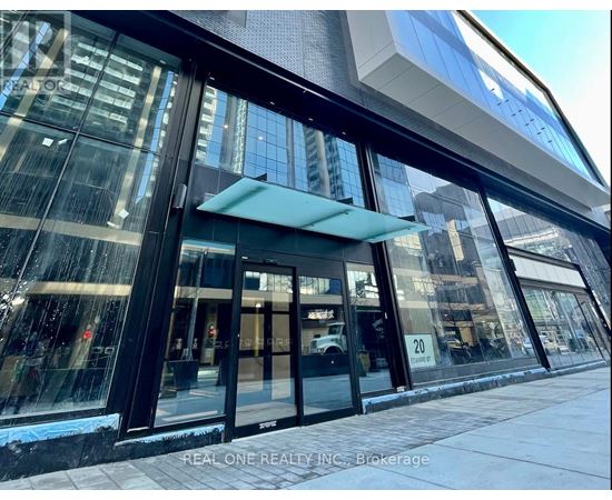 The image shows the front of a building with a glass facade and a blue awning.
