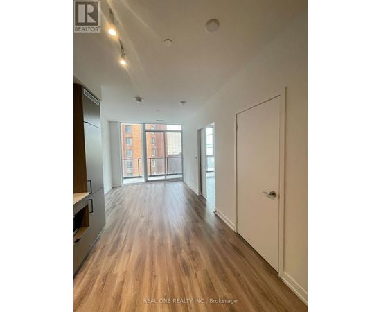 A spacious room with wooden floors and a large window.
