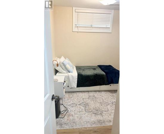 A bedroom with a bed, pillows, and a rug.
