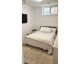 A bedroom with a bed, a nightstand, and a window.