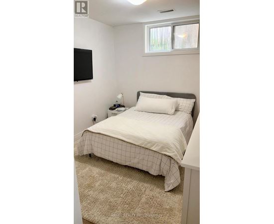 A bedroom with a bed, a nightstand, and a window.
