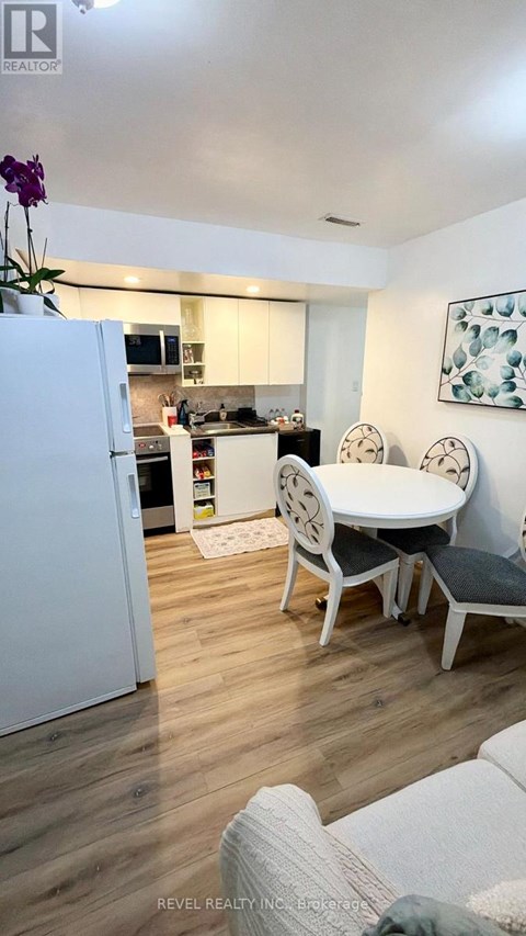 A white refrigerator is in a kitchen with a table and chairs.