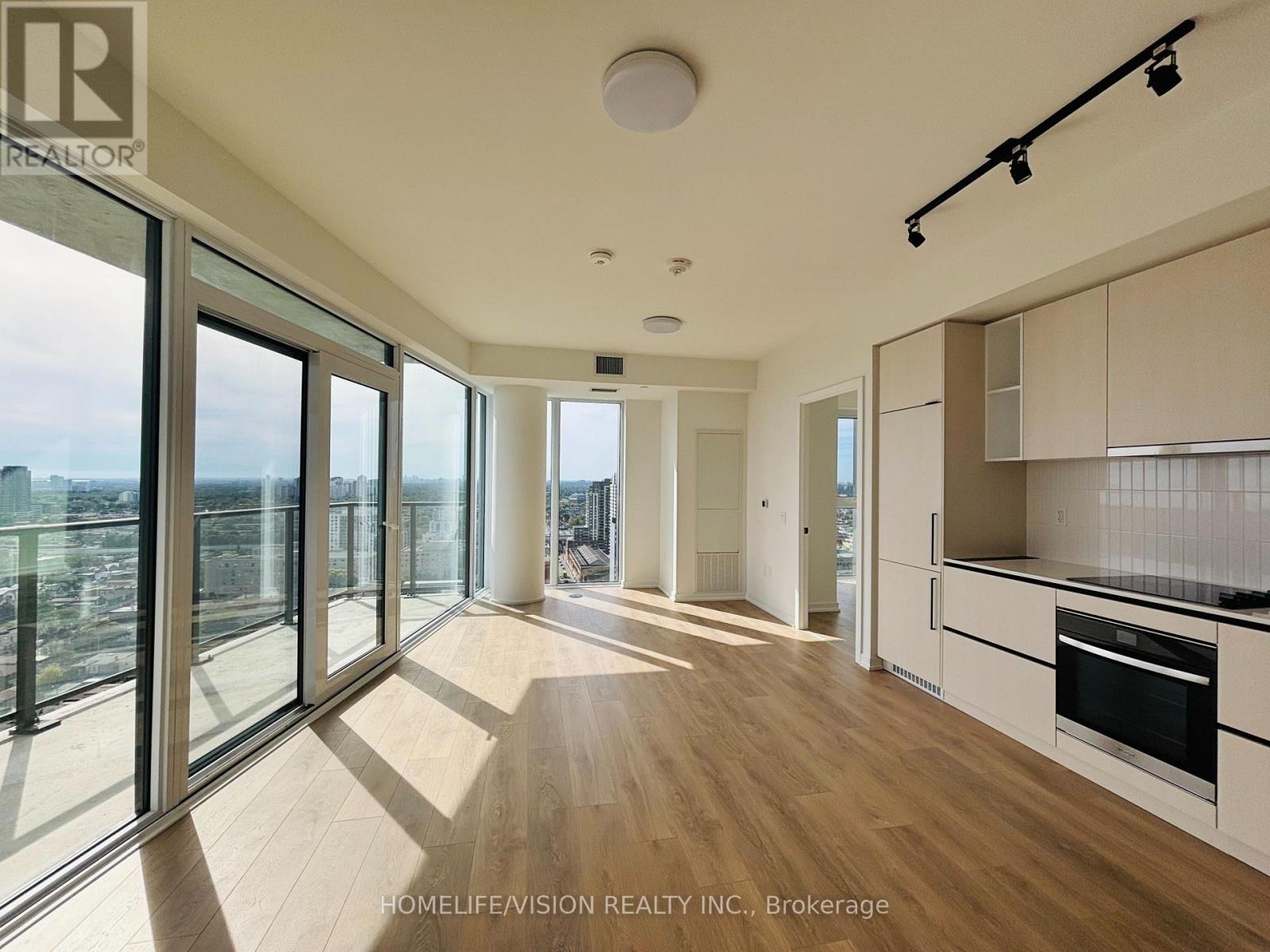 A spacious kitchen with white cabinets and a large window overlooking the city.