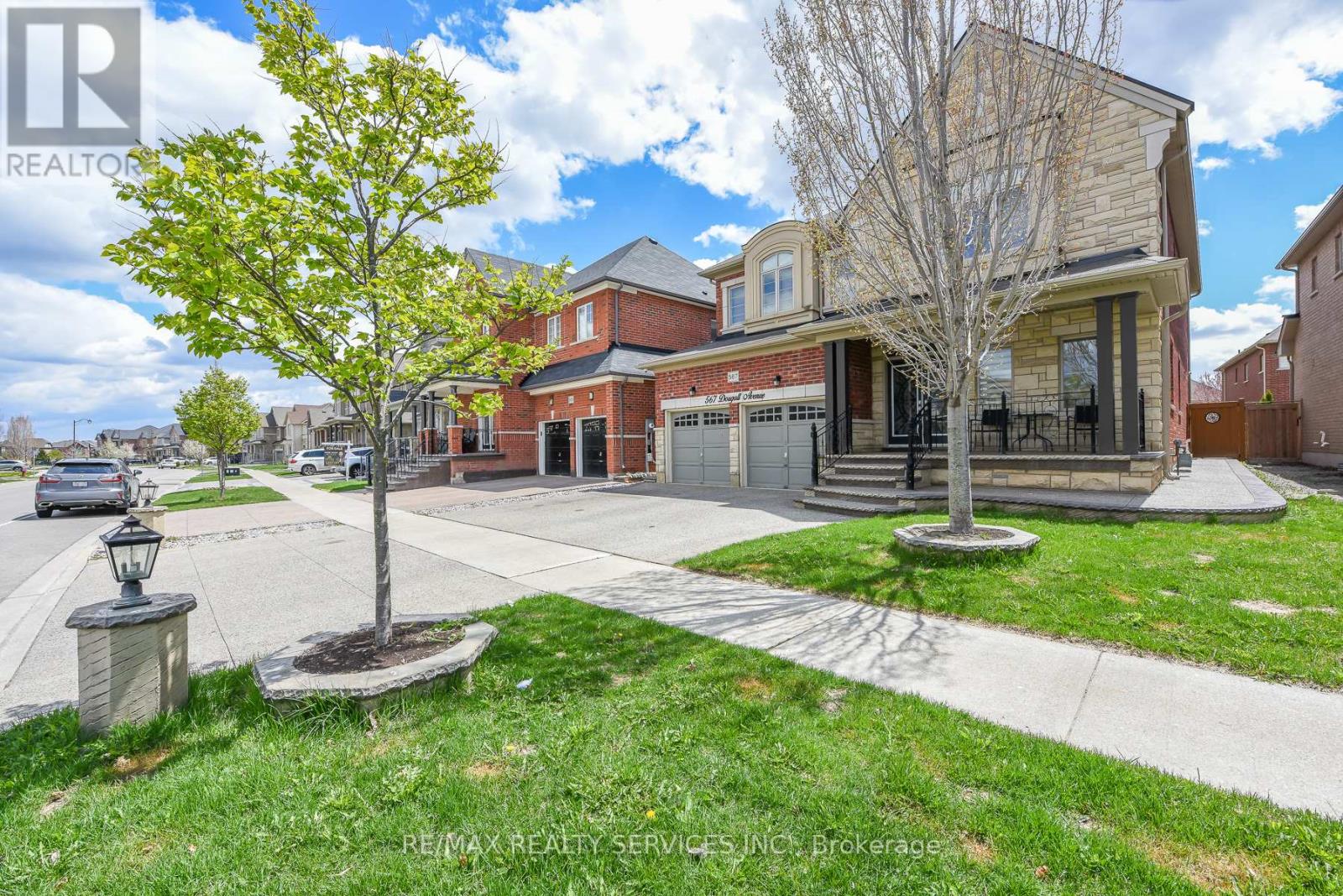 A tree stands in a grassy area in front of a house.