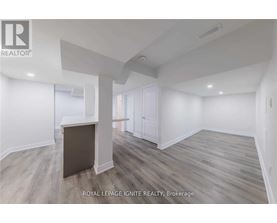 A spacious room with wooden flooring and white walls.
