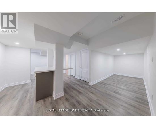 A spacious room with wooden flooring and white walls.