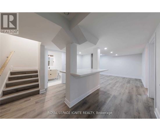 A spacious room with wooden flooring and white walls.