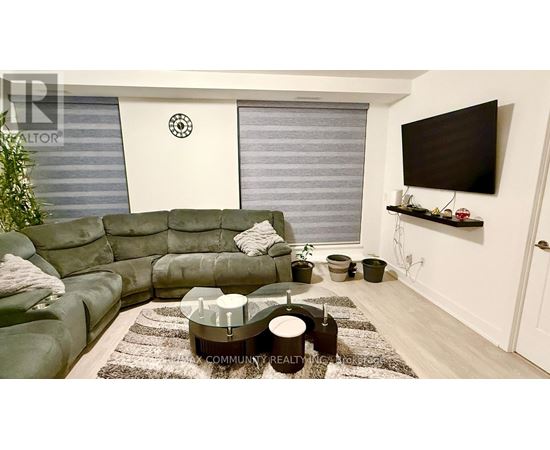 A living room with a green sofa and a flat screen TV mounted on the wall.