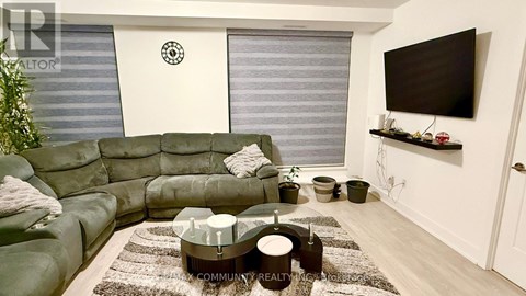 A living room with a green sofa and a flat screen TV mounted on the wall.