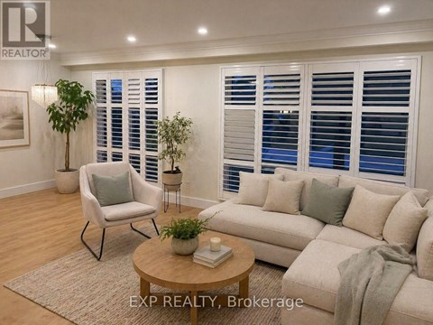 A well-lit living room with a beige sofa, a chair, and a small table with a plant on it.