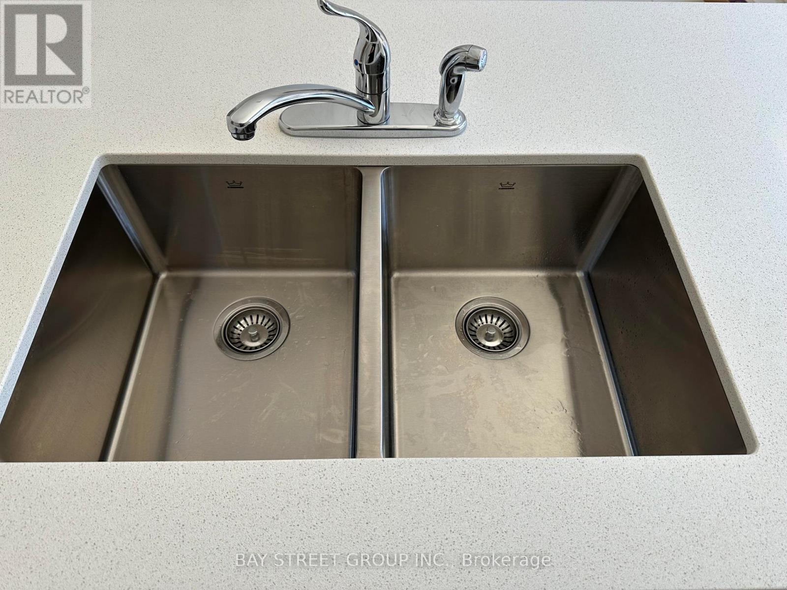 A double sink in a kitchen with a faucet above it.