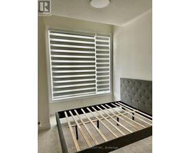 A bedroom with a bed, window with blinds, and a headboard.