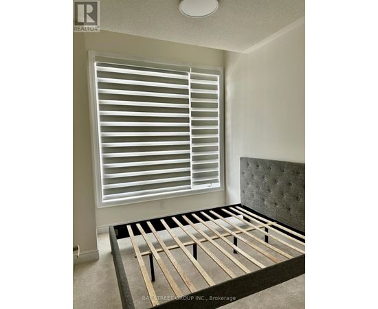 A bedroom with a bed, window with blinds, and a headboard.