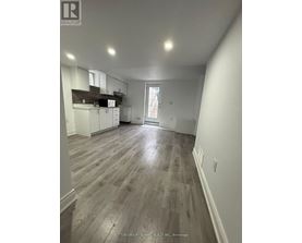 A spacious room with wooden flooring and white walls.