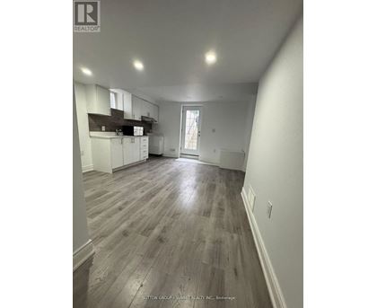 A spacious room with wooden flooring and white walls.