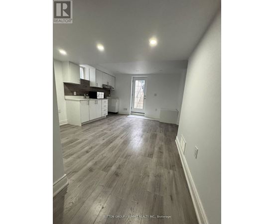 A spacious room with wooden flooring and white walls.