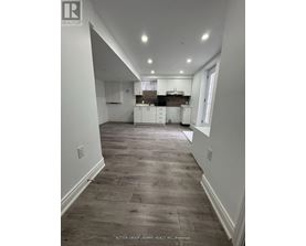 A spacious kitchen with white cabinets and a wooden floor.
