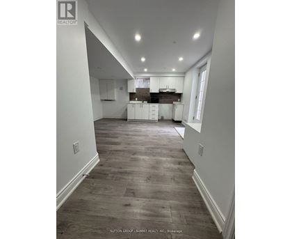 A spacious kitchen with white cabinets and a wooden floor.