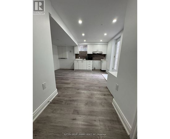 A spacious kitchen with white cabinets and a wooden floor.
