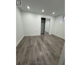 A room with wood flooring and a doorway leading to another room.