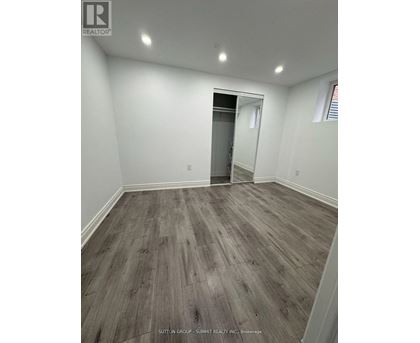 A room with wood flooring and a doorway leading to another room.