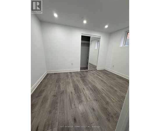 A room with wood flooring and a doorway leading to another room.