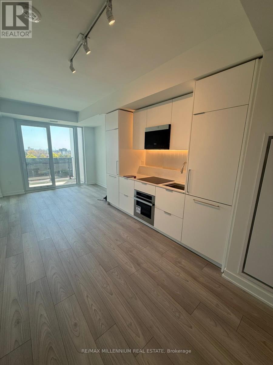 A modern kitchen with white cabinets and a wooden floor.