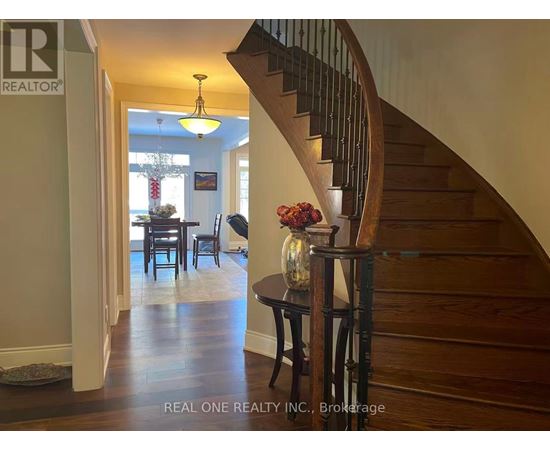 A wooden staircase with a glass railing and a table with a vase of flowers on it.
