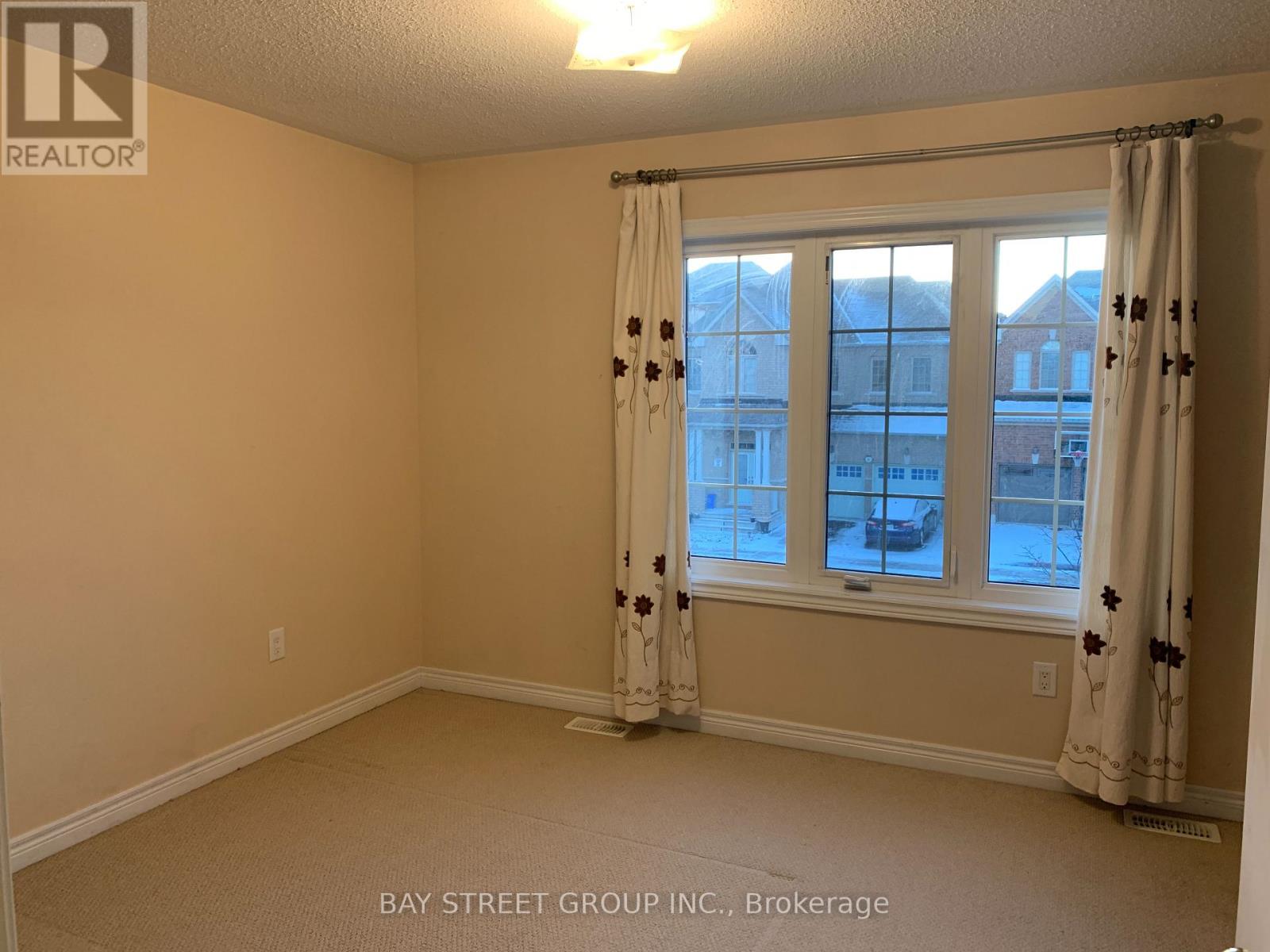 A room with a window and curtains, with a view of buildings outside.