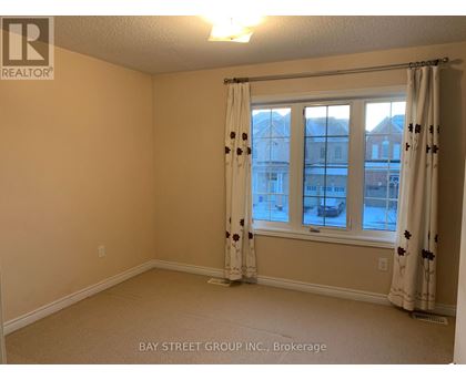 A room with a window and curtains, with a view of buildings outside.