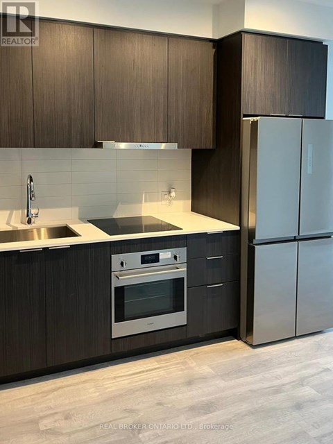 A modern kitchen with dark wood cabinets and stainless steel appliances.