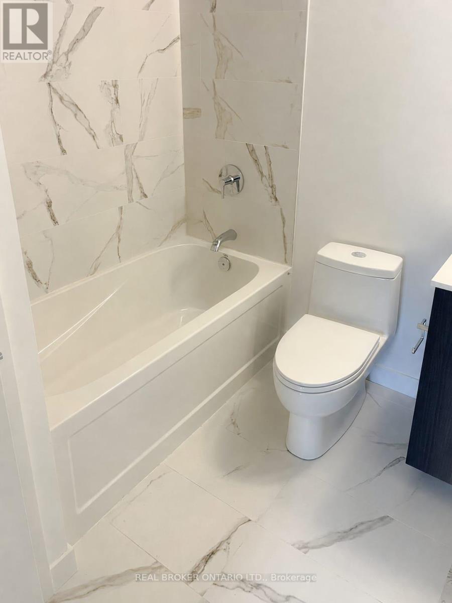 A white toilet sits next to a bathtub in a bathroom with marble walls and floor.