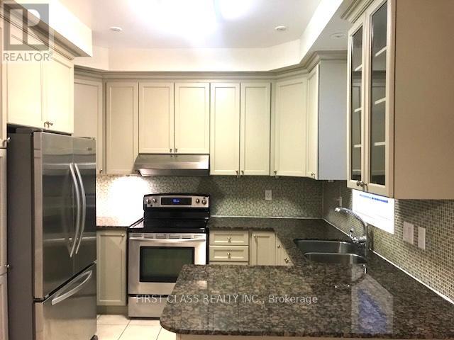 A kitchen with a refrigerator, microwave, oven, sink and cabinets.