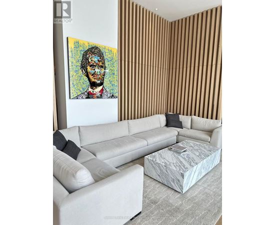 A living room with a white couch and a painting of a man on the wall.