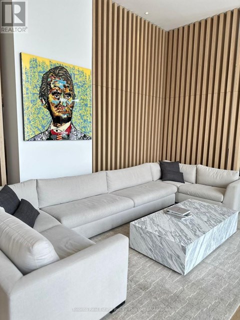 A living room with a white couch and a painting of a man on the wall.