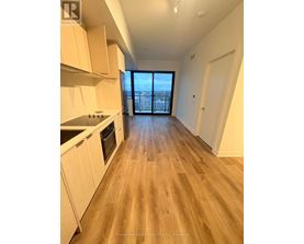A spacious kitchen with wooden flooring and white cabinets.