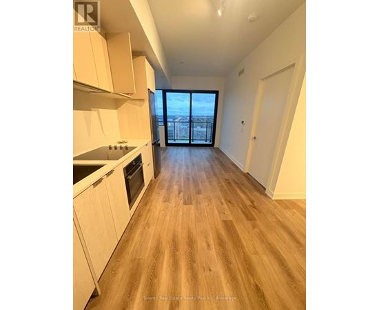 A spacious kitchen with wooden flooring and white cabinets.